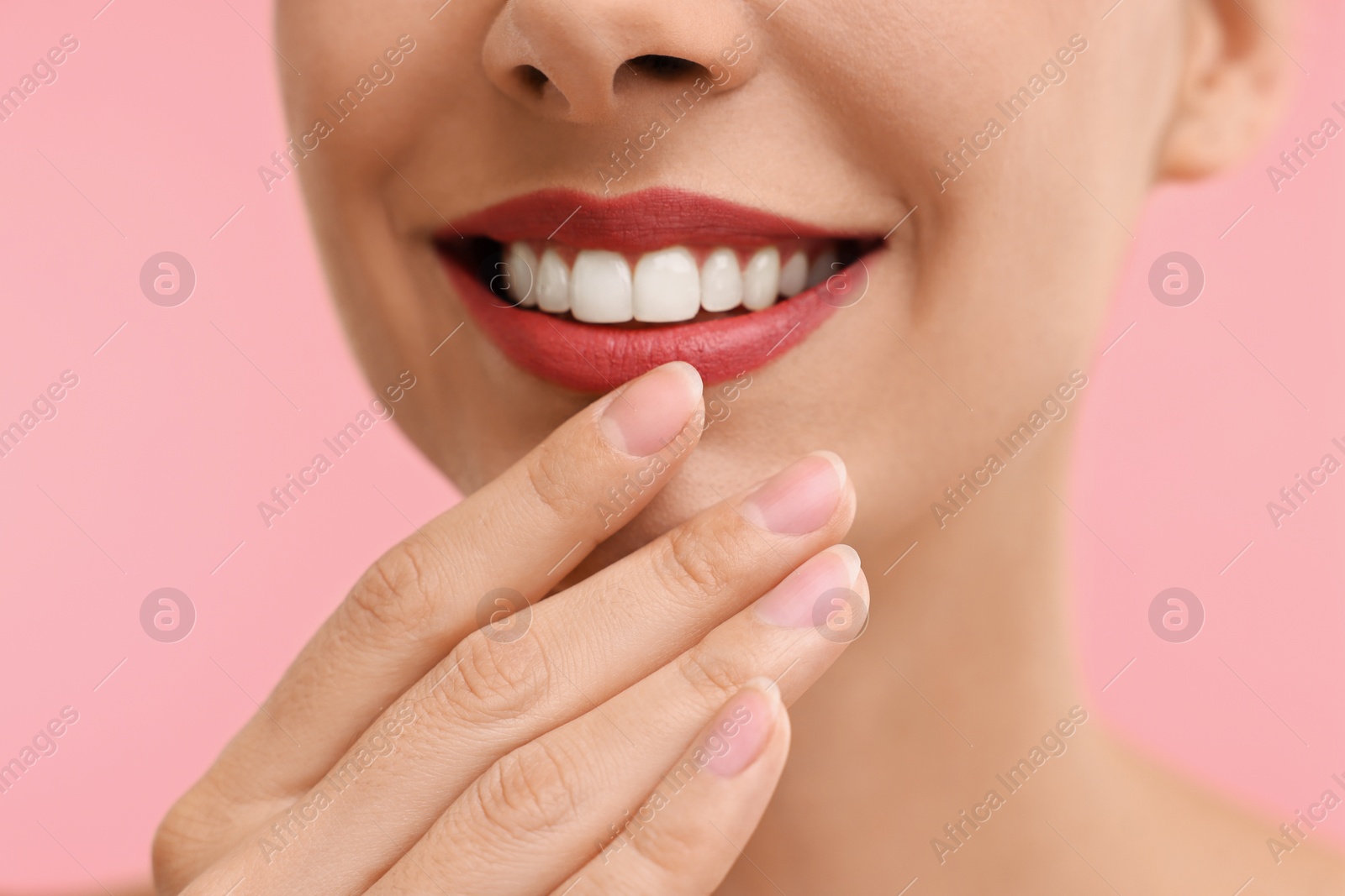 Photo of Woman with beautiful lips smiling on pink background, closeup