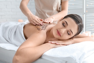 Photo of Young woman having body scrubbing procedure in spa salon