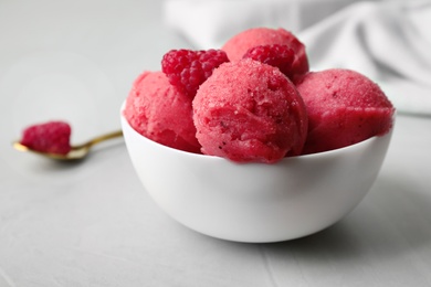 Photo of Delicious pink ice cream with raspberries in bowl on grey table