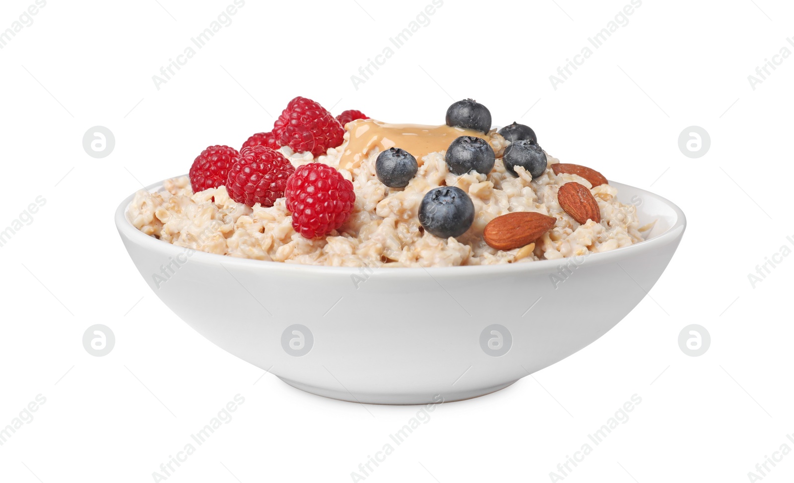 Photo of Tasty boiled oatmeal with berries, almonds and peanut butter in bowl isolated on white