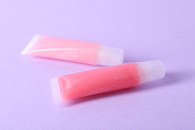 Photo of Different lip balms on lilac background, closeup