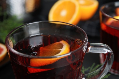 Photo of Tasty mulled wine in glass cup on table, closeup