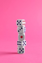 Many stacked game dices on pink background