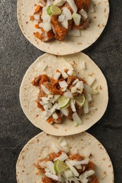 Delicious tacos with vegetables, meat and lime on grey textured table, flat lay