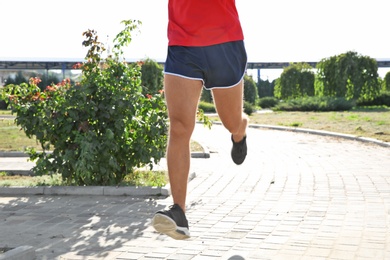 Sporty man running outdoors on sunny morning