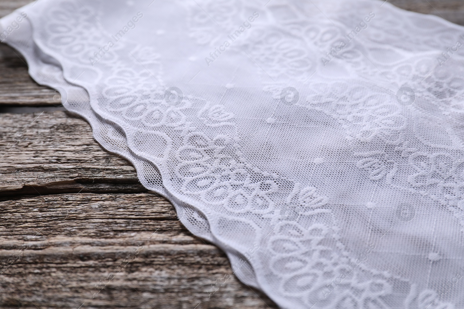 Photo of White lace with beautiful pattern on wooden table, closeup