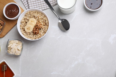 Photo of Tasty breakfast with oatmeal porridge on light grey marble table, flat lay. Space for text