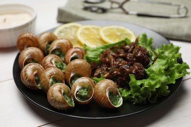 Photo of Delicious cooked snails served on white wooden table, closeup