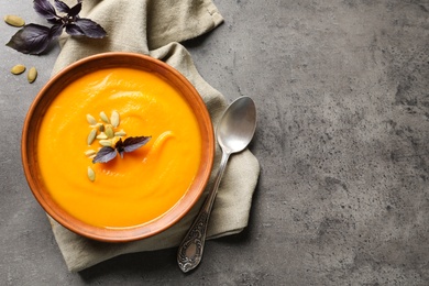 Photo of Flat lay composition with bowl of pumpkin soup and space for text on gray background