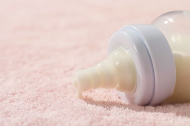 Photo of Feeding bottle with baby formula on soft towel, closeup. Space for text