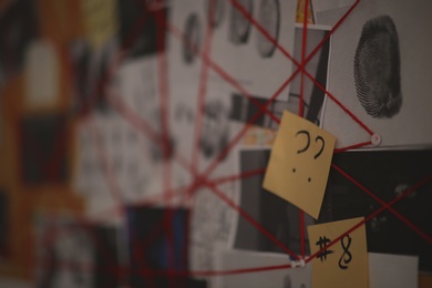 Detective board with sticker, fingerprints and red threads, closeup