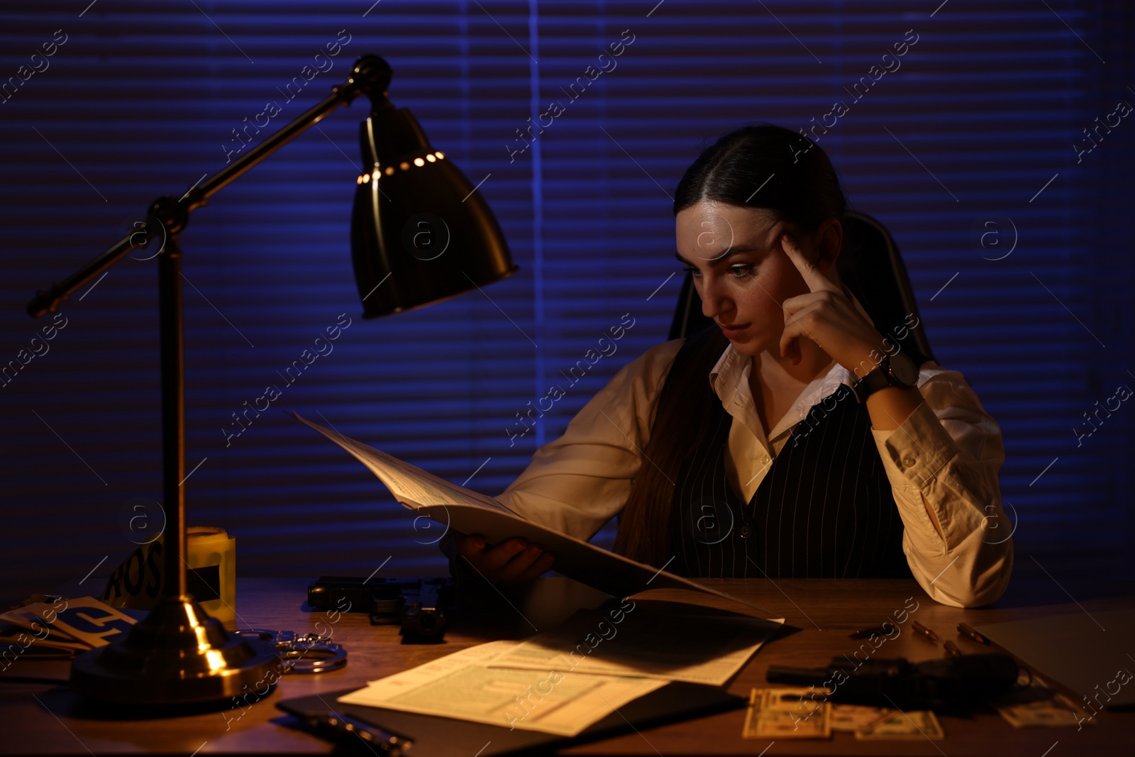 Photo of Professional detective working with documents in office at night