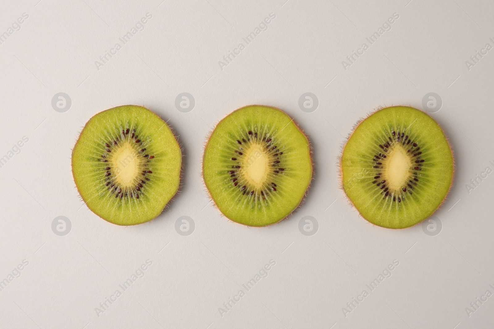 Photo of Cut fresh ripe kiwis on white background, flat lay