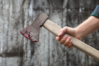 Photo of Man holding bloody axe outdoors, closeup view
