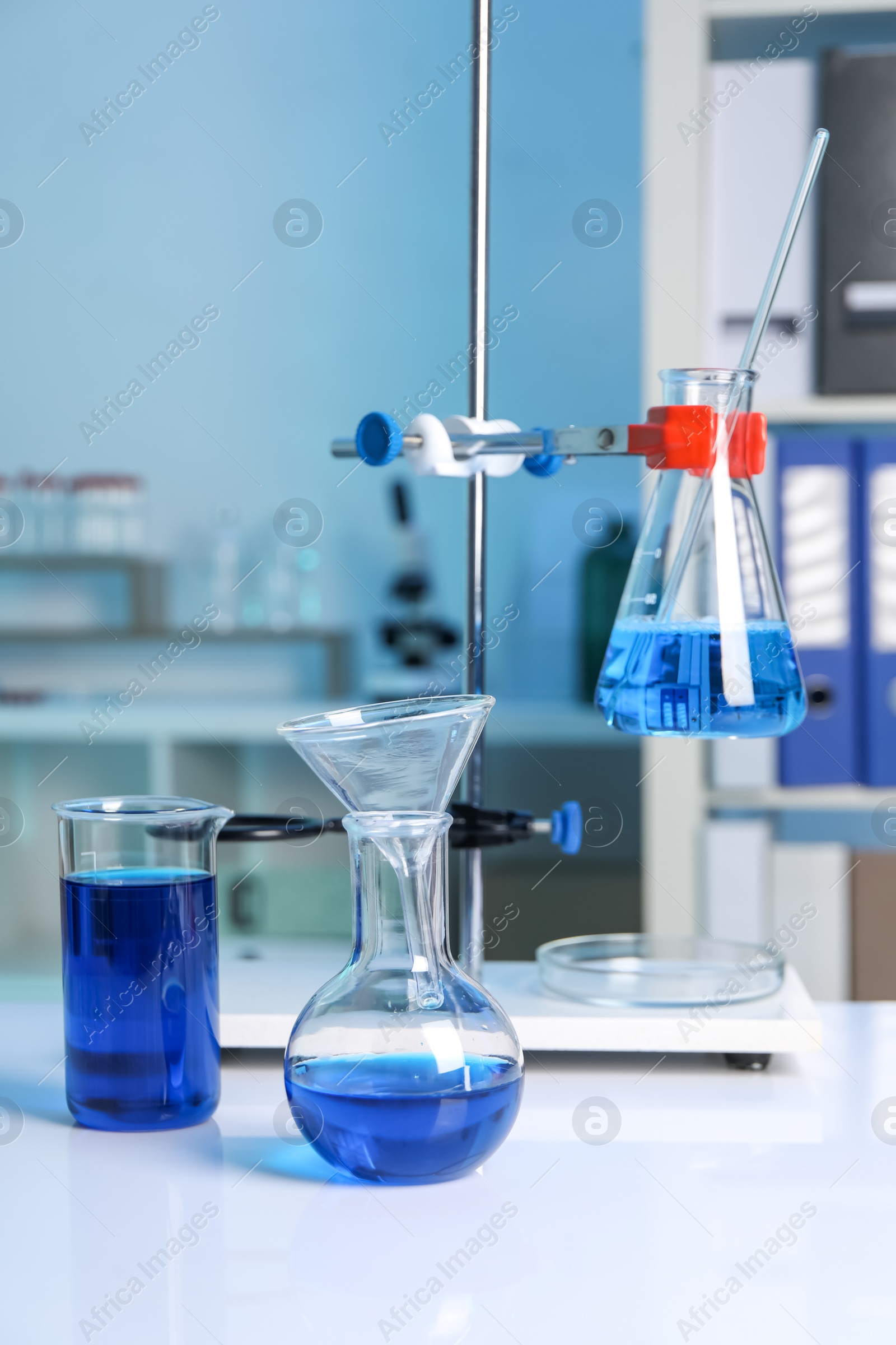 Photo of Laboratory analysis. Flasks and beaker with blue liquid on white table indoors