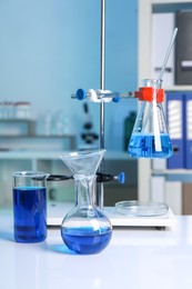 Laboratory analysis. Flasks and beaker with blue liquid on white table indoors