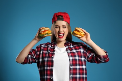 Photo of Pretty woman with tasty burgers on color background