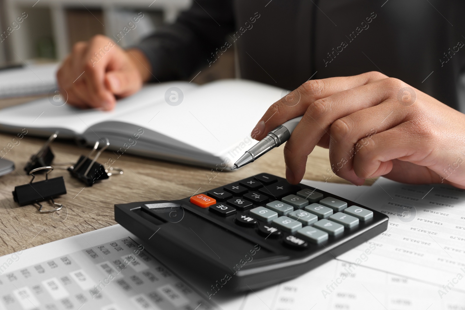 Photo of Woman using calculator at wooden table, closeup