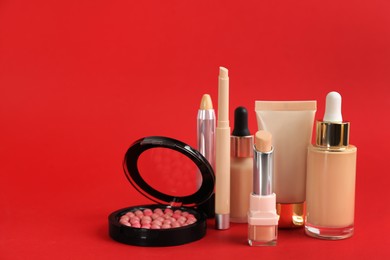 Photo of Foundation makeup products on red background, space for text. Decorative cosmetics