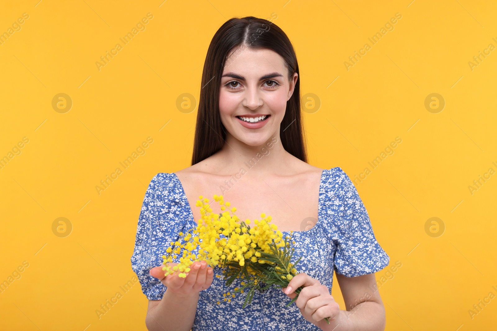 Photo of Happy young woman with beautiful bouquet on orange background