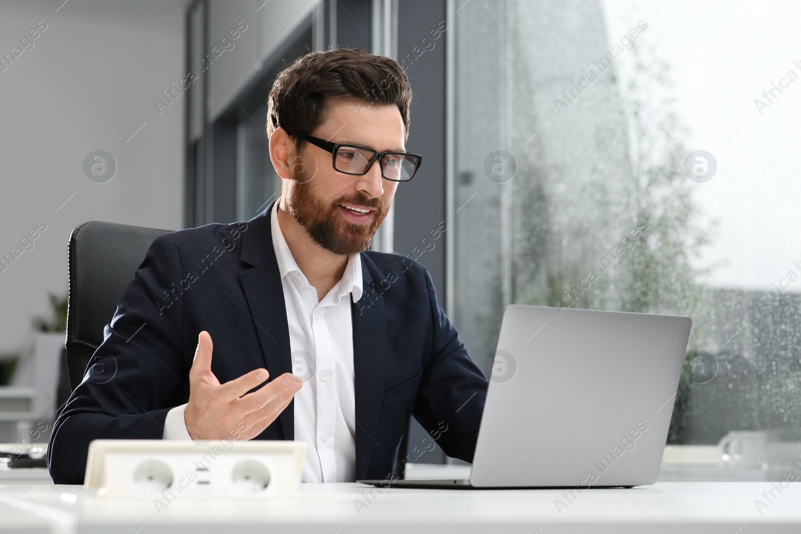 Photo of Man working on laptop at white desk in office