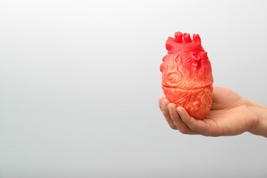 Photo of Man holding model of heart on light background. Heart attack concept