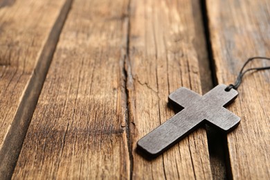 Photo of Christian cross on wooden table, closeup. Space for text