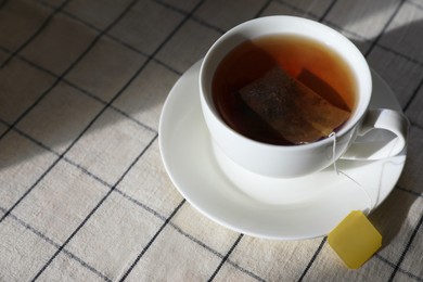Photo of Bag of black tea in cup on table. Space for text