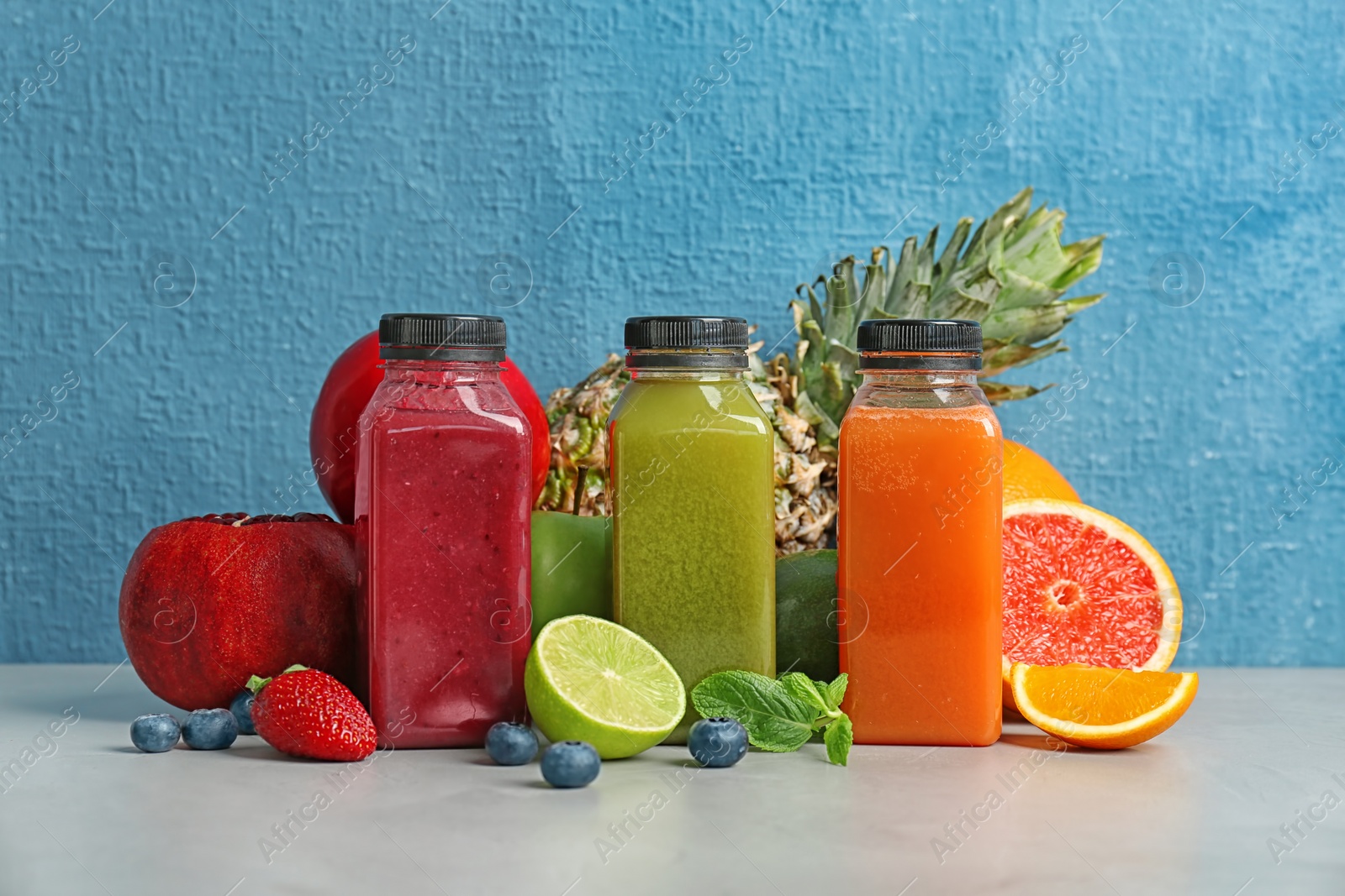 Photo of Bottles with healthy detox smoothies and ingredients on table