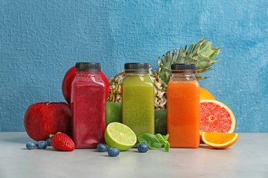 Photo of Bottles with healthy detox smoothies and ingredients on table