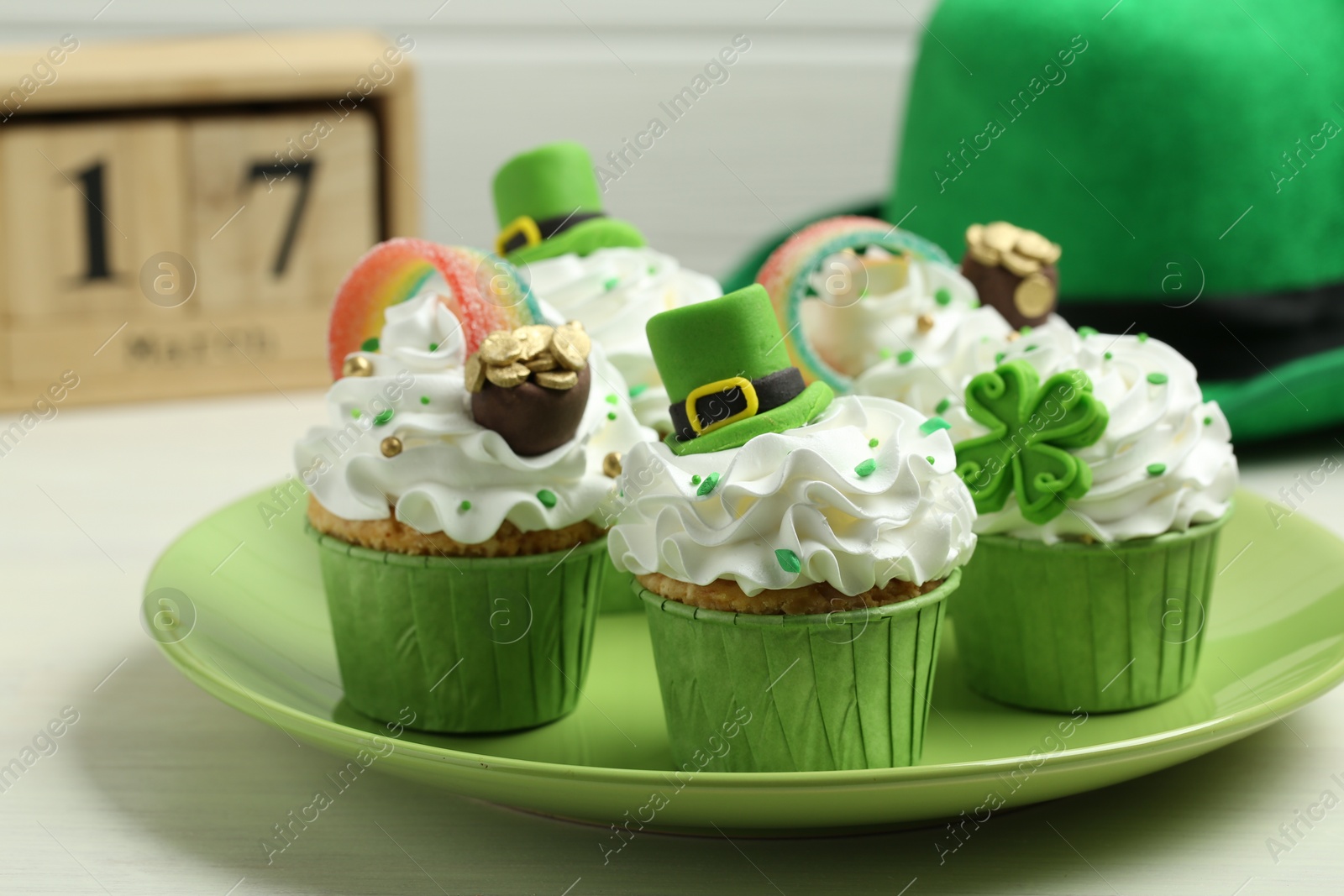 Photo of St. Patrick's day party. Tasty festively decorated cupcakes on white table, closeup