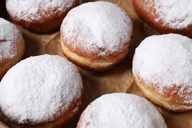Delicious buns with powdered sugar on parchment paper, closeup