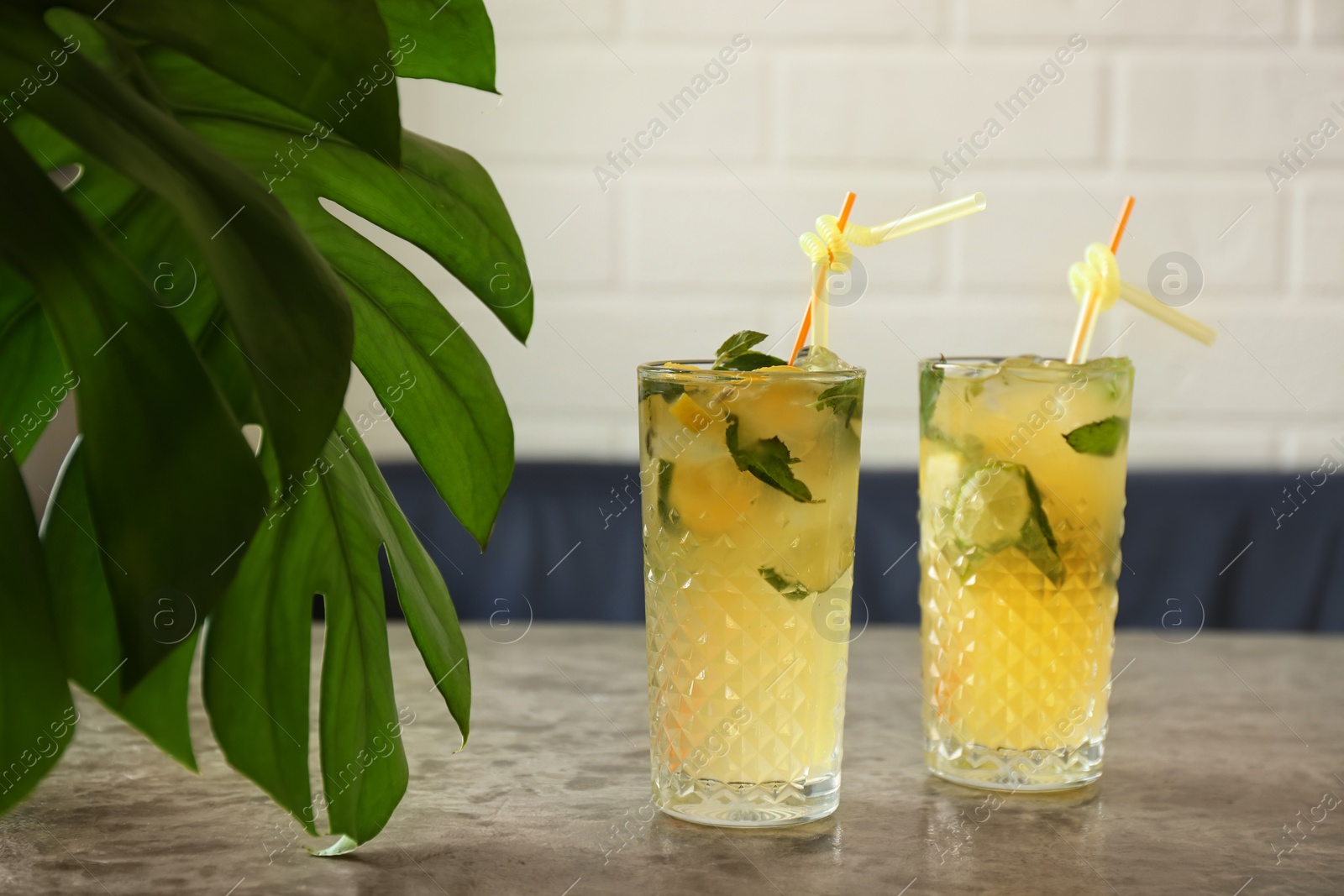 Photo of Glasses of iced lemonade on table indoors