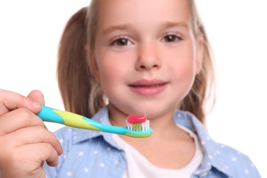 Photo of Little girl holding toothbrush with paste on white background, closeup