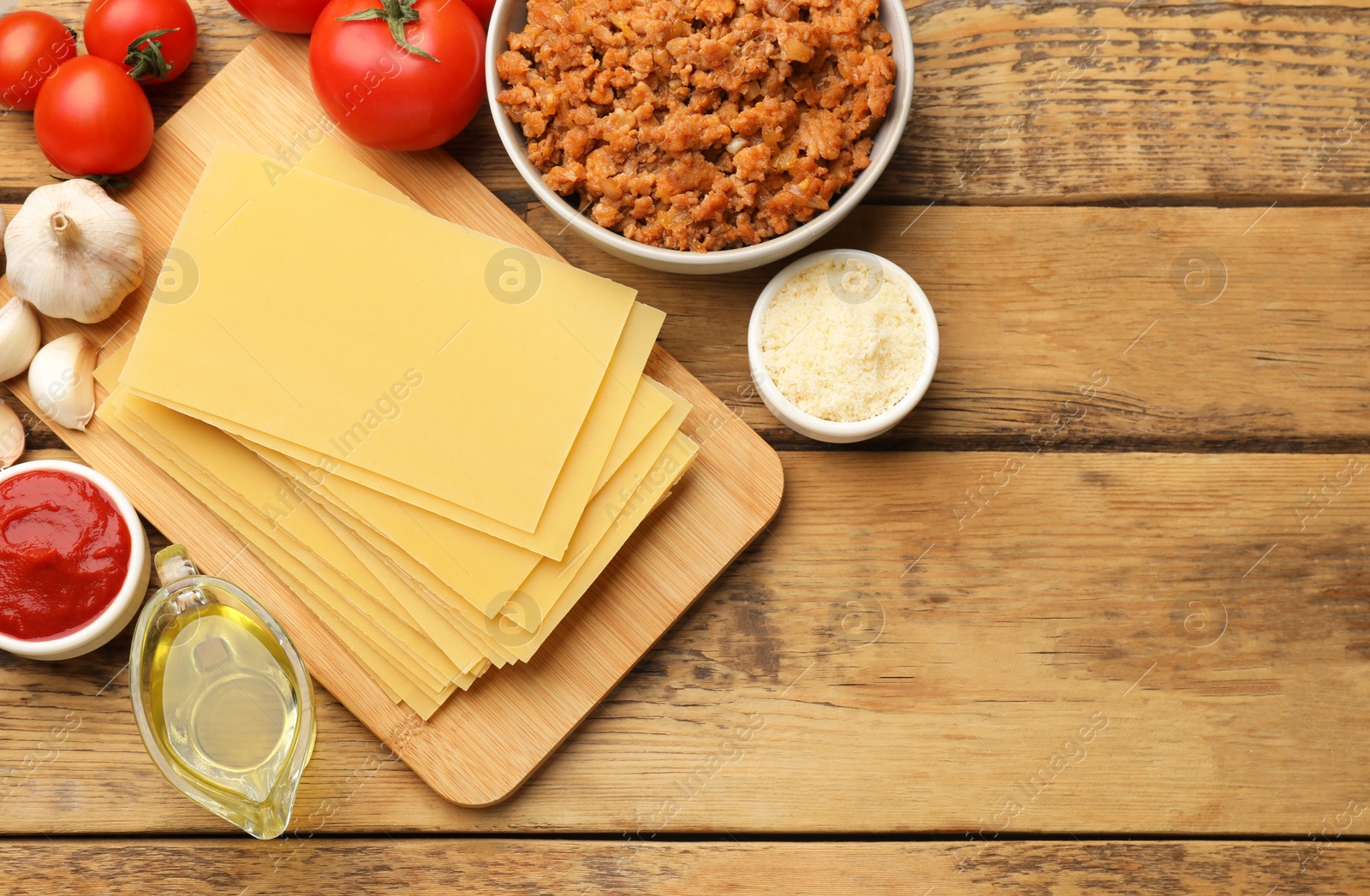 Photo of Flat lay composition with products for cooking lasagna on wooden table. Space for text