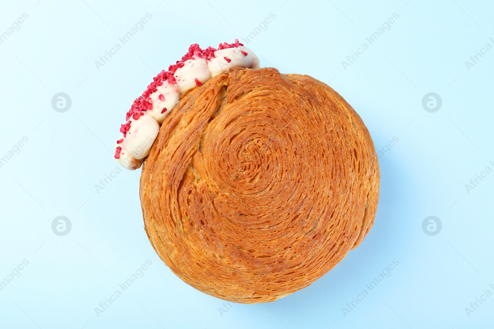 Photo of One supreme croissant with cream on light blue background, top view. Tasty puff pastry