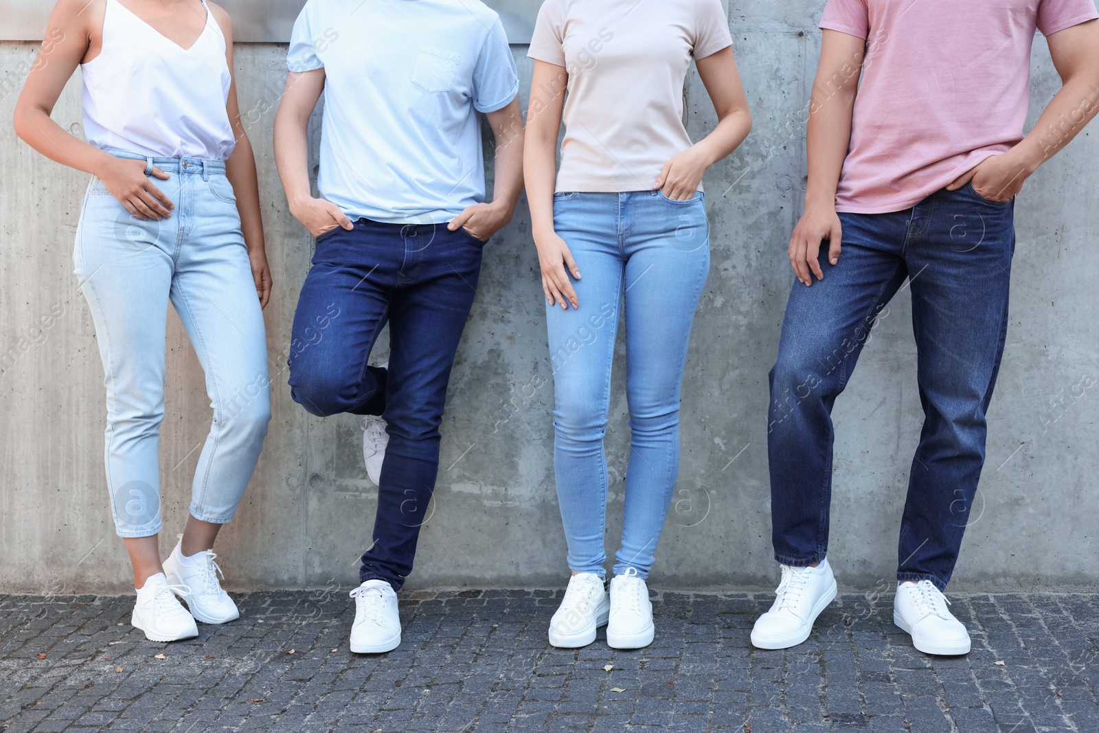 Photo of Group of people in stylish jeans near grey wall outdoors, closeup