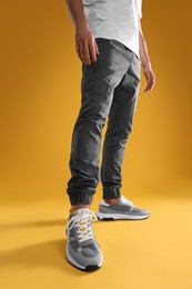 Photo of Man wearing stylish sneakers on yellow background, closeup