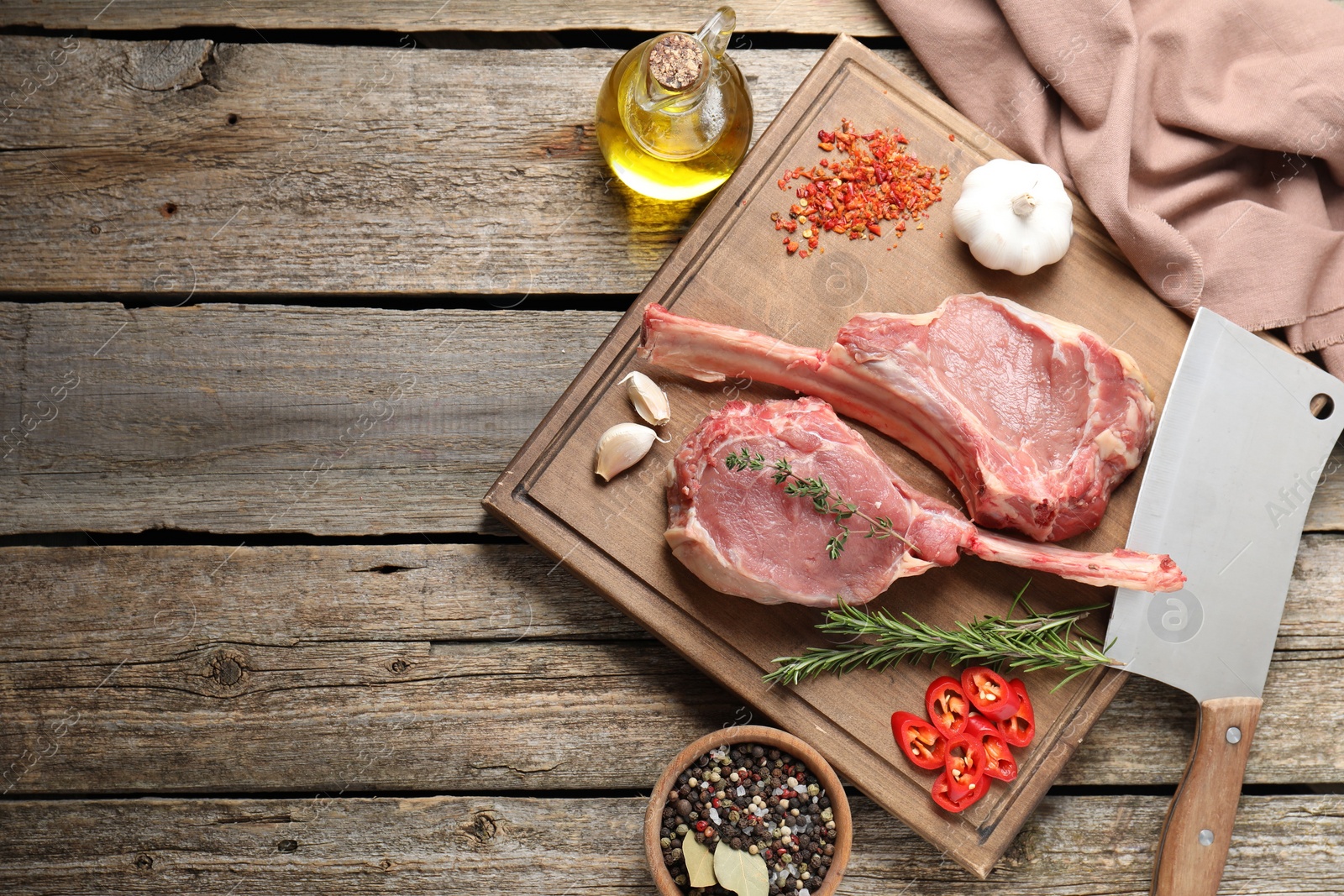 Photo of Fresh tomahawk beef cuts, butcher knife and spices on wooden table, top view. Space for text