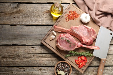 Photo of Fresh tomahawk beef cuts, butcher knife and spices on wooden table, top view. Space for text