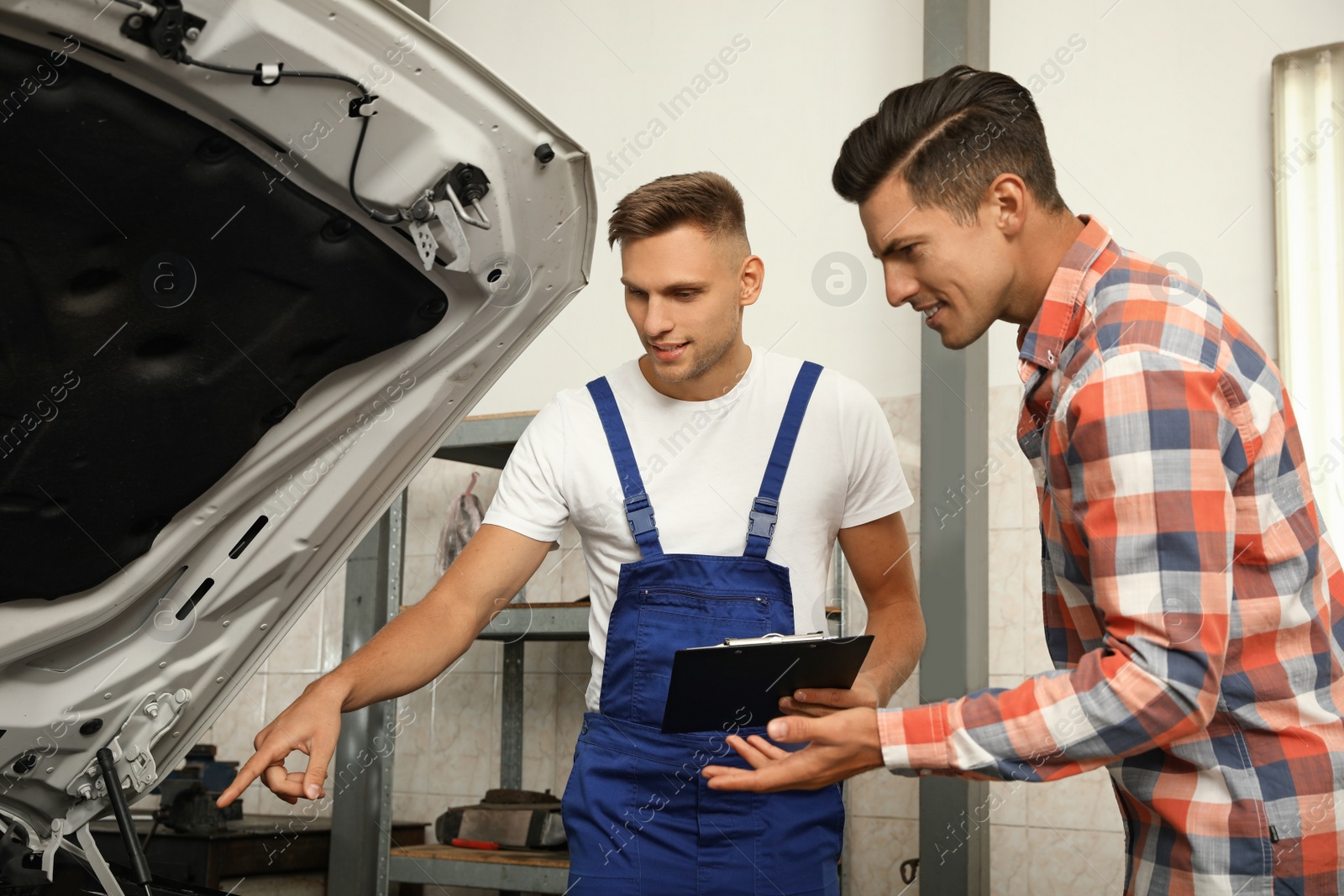 Photo of Mechanic and client near car at automobile repair shop