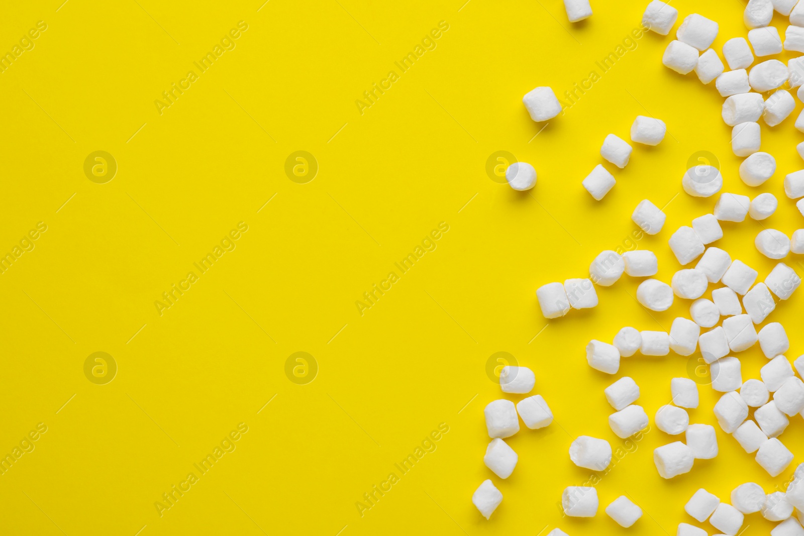 Photo of Delicious marshmallows on yellow background, flat lay. Space for text