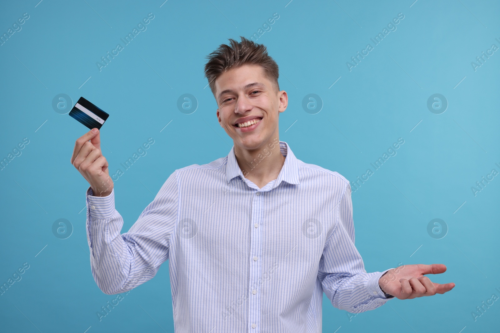 Photo of Happy man with credit card on light blue background