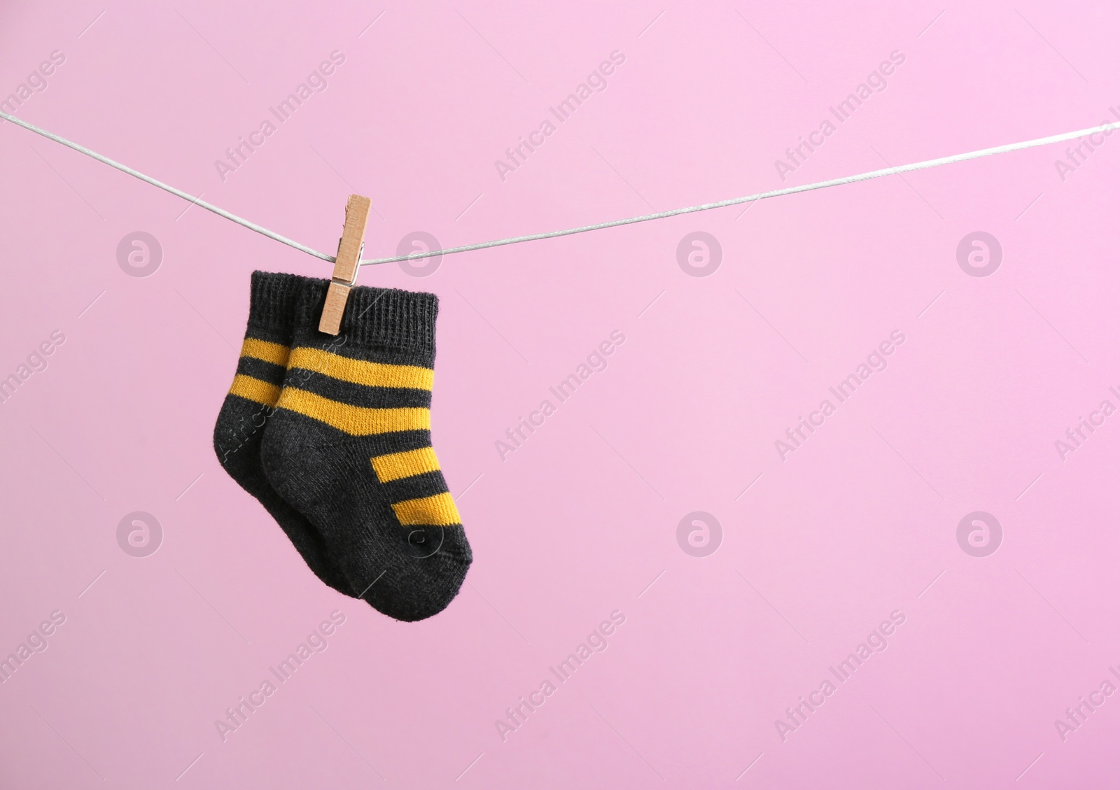 Photo of Small socks hanging on washing line against color background, space for text. Baby accessories