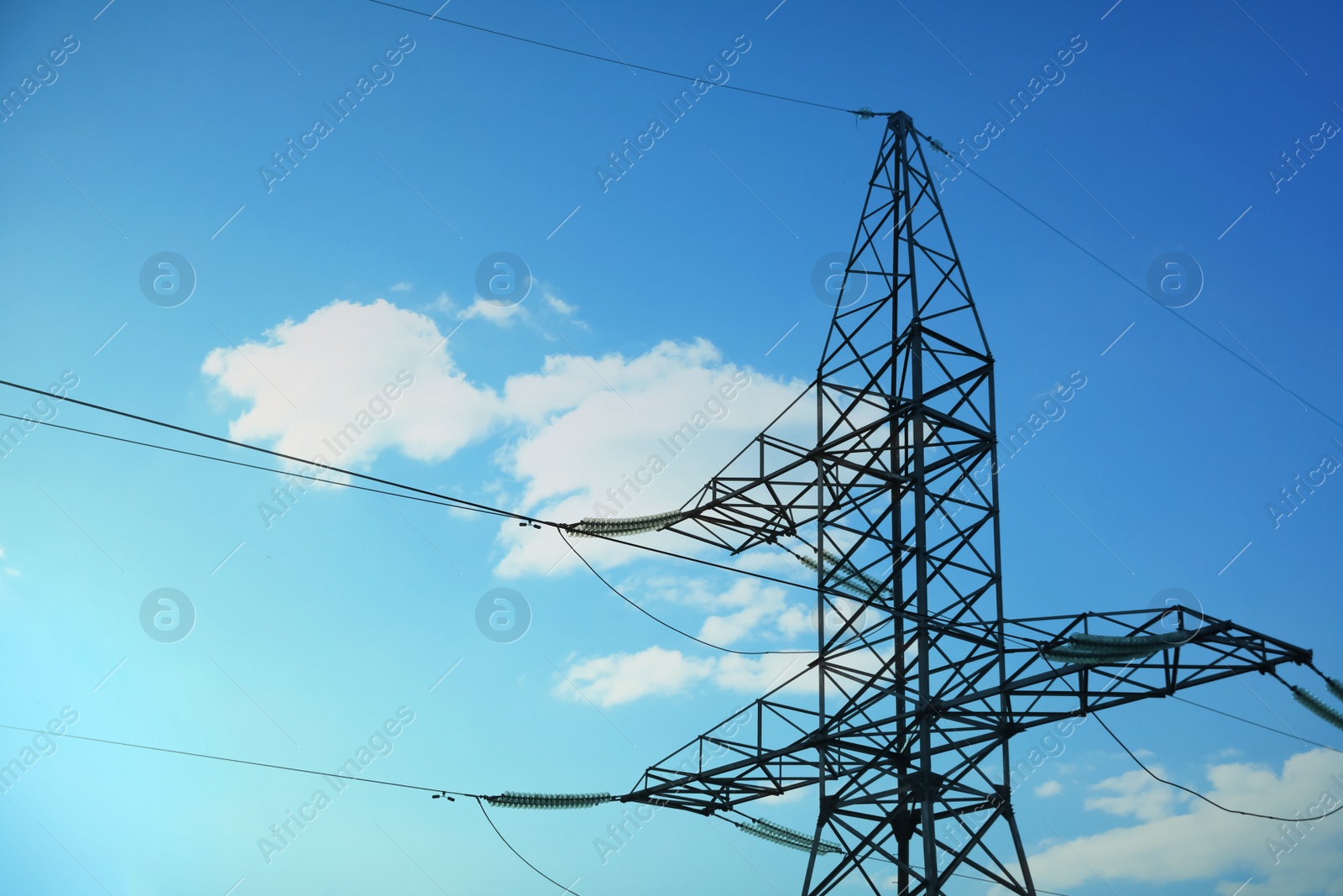 Photo of High voltage tower against blue sky on sunny day