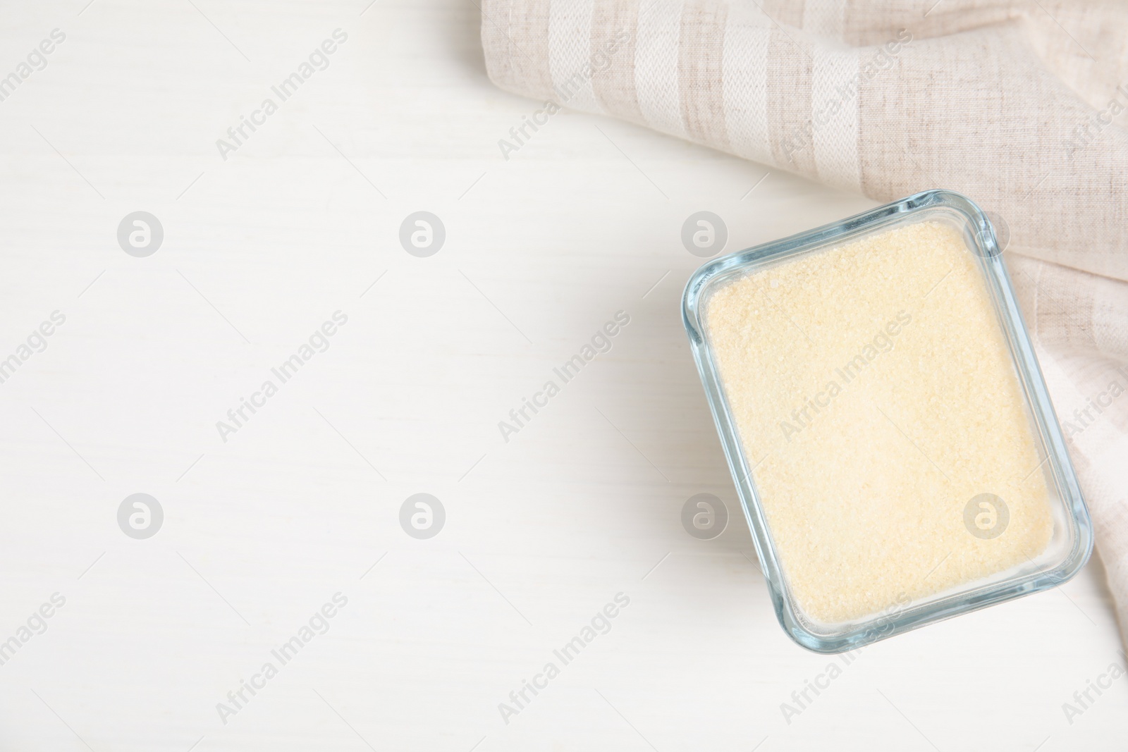 Photo of Gelatin powder in glass bowl on white table, top view. Space for text