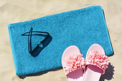 Towel, flip flops and sunglasses on sand, flat lay. Beach accessories