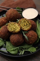 Delicious falafel balls, herbs and sauce on table