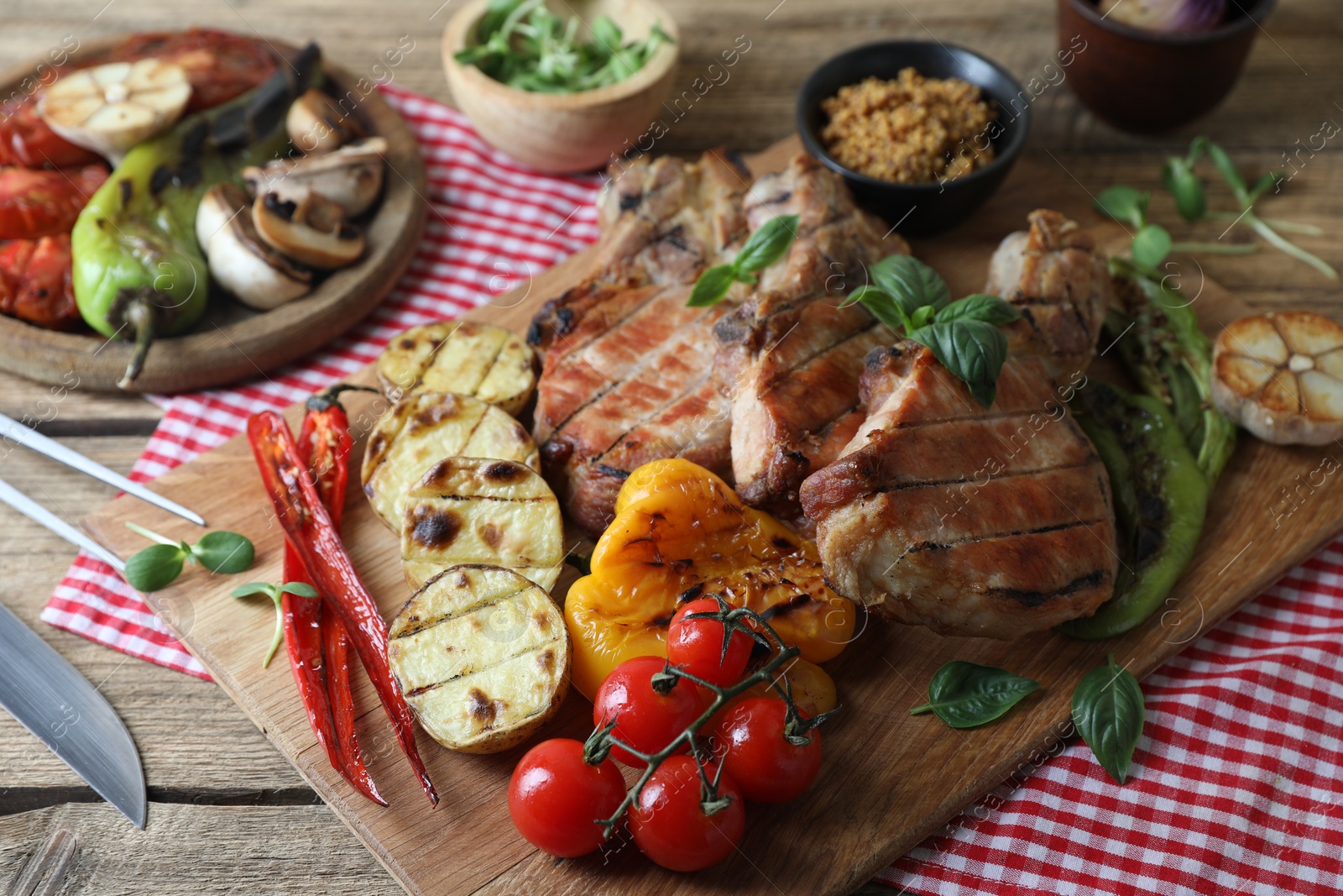 Photo of Delicious grilled meat and vegetables served on wooden table, closeup