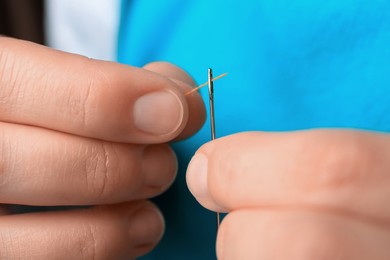 Closeup view of woman threading sewing needle